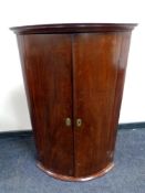 An early 19th century mahogany bow fronted corner cabinet