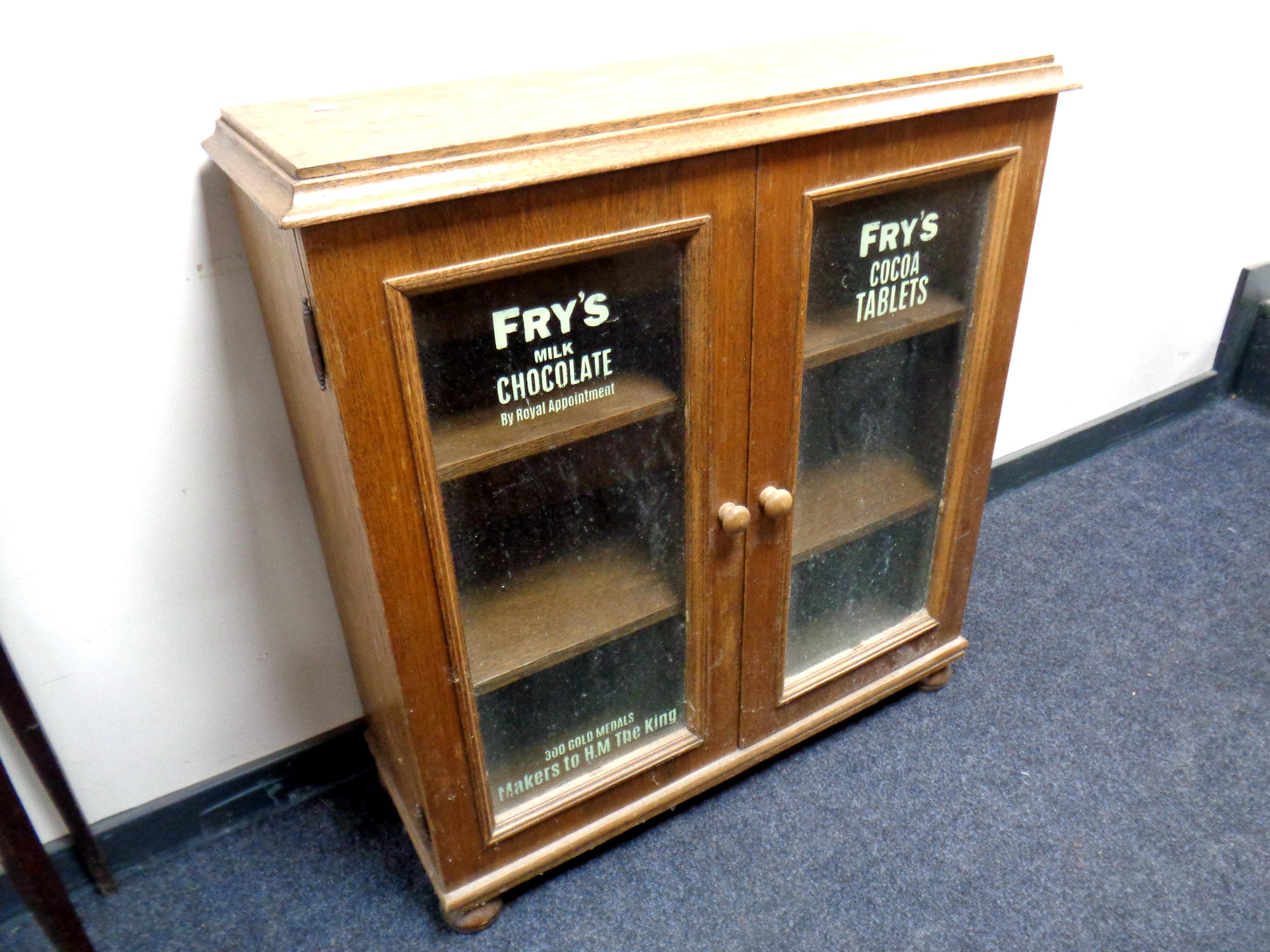 An oak double door glazed bookcase on bun feet bearing later Fry's advertising