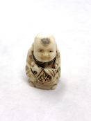 A Japanese craved bone netsuke : A young man holding a large carp.