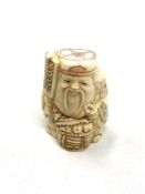 A Japanese craved bone netsuke : A village elder with a basket at his feet.