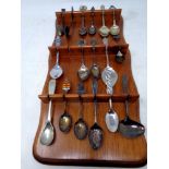 A wooden spoon rack containing fifteen plated and silver tea spoons