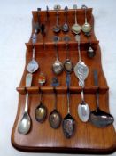 A wooden spoon rack containing fifteen plated and silver tea spoons