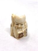 A Japanese craved bone netsuke : A village elder holding a scroll.