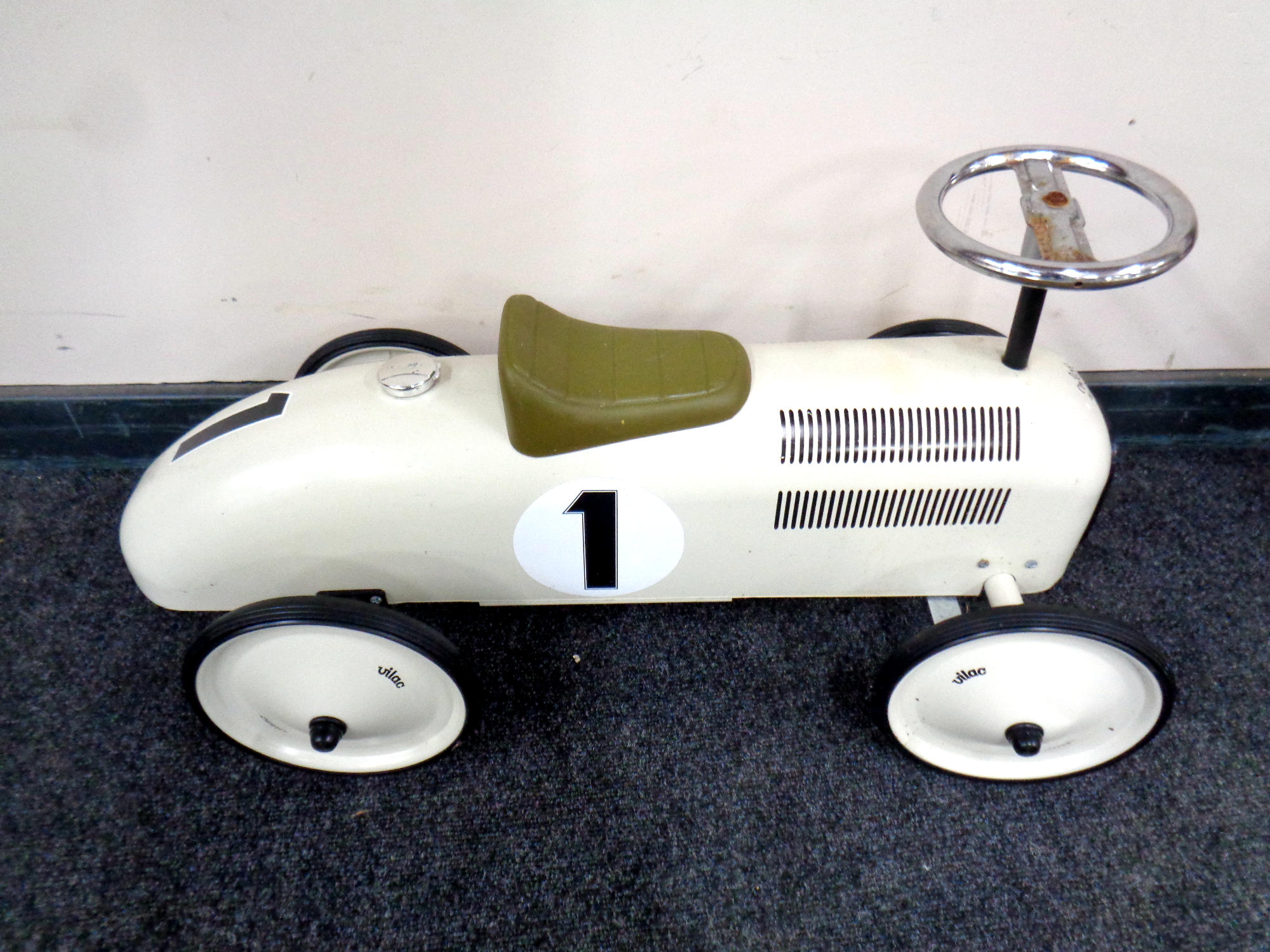 A child's tin ride on car in the form of an early 20th century racing car