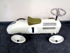 A child's tin ride on car in the form of an early 20th century racing car