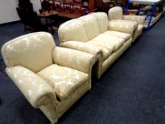 An Edwardian three piece lounge suite upholstered in a gold classical print