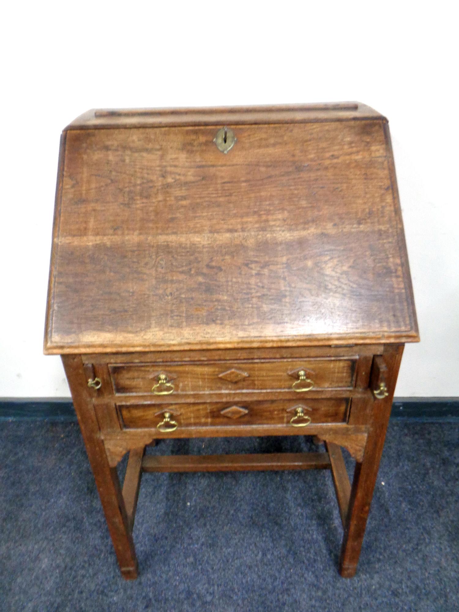 An Edwardian oak lady's bureau fitted two drawers beneath on raised legs,