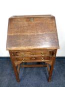 An Edwardian oak lady's bureau fitted two drawers beneath on raised legs,
