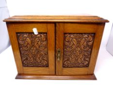 An Edwardian carved oak double door smoker's cabinet