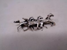 A silver brooch modelled as three horses