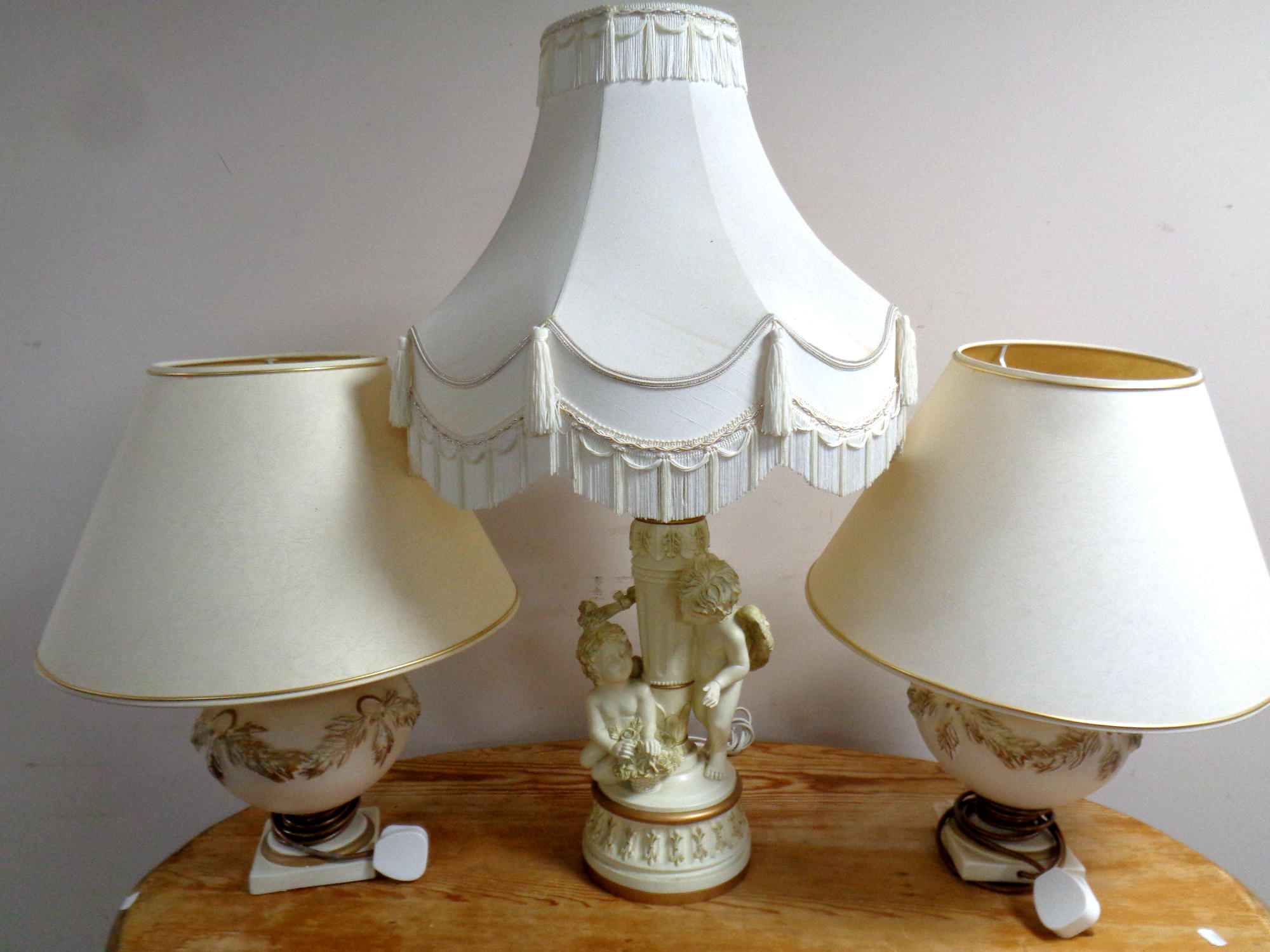 A contemporary cherub composite table lamp with tasselled shade together with a further pair of