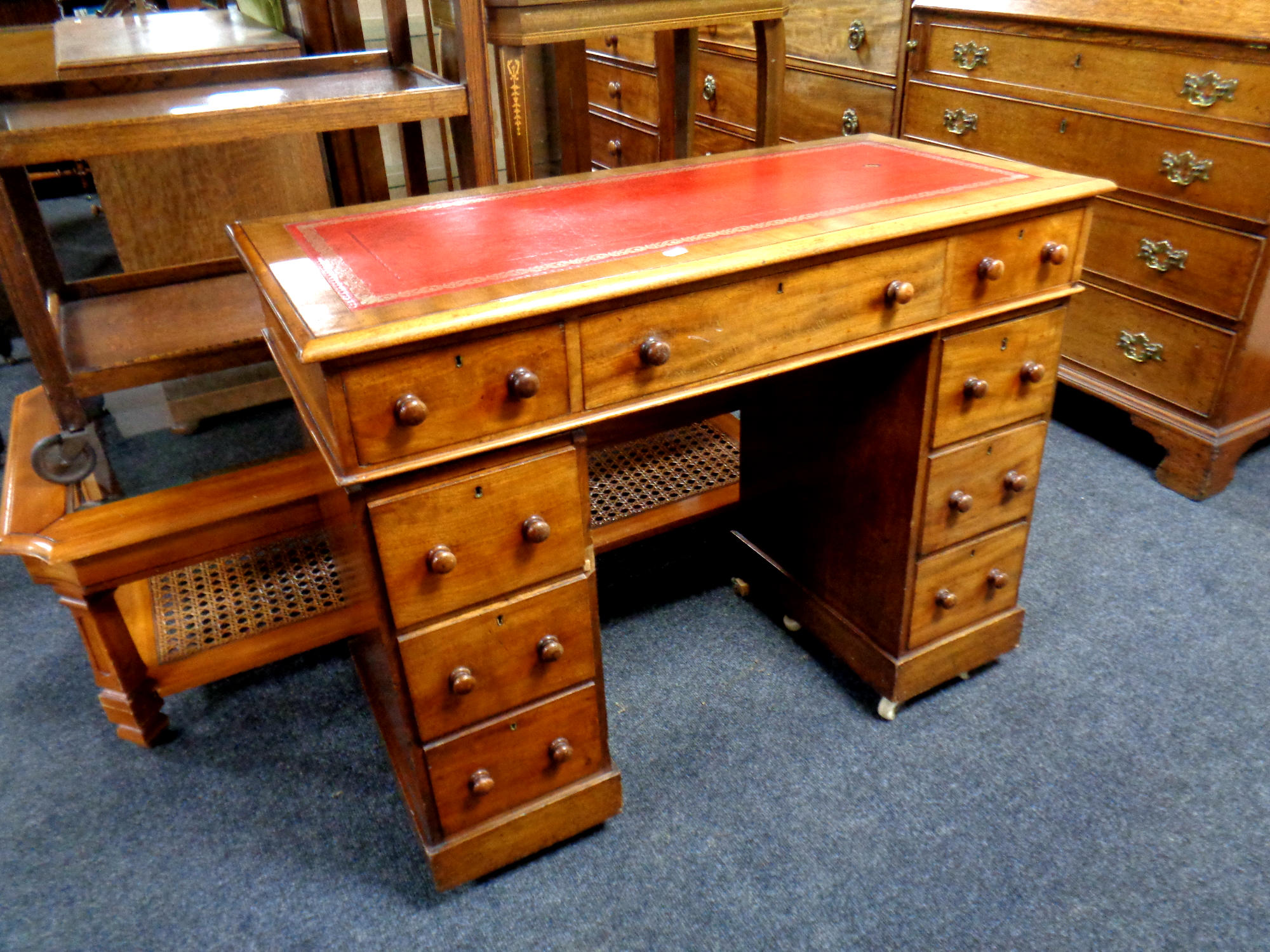 A Victorian mahogany child's desk fitted nine drawers with a red leather inset panel,