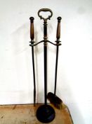 An antique brass two piece fire companion set on stand