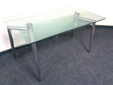 A contemporary glass topped dining table on metal legs,