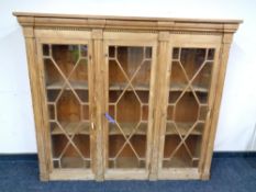 A stripped pine triple door bookcase with astral glazed doors,