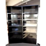 A pair of black high gloss open bookshelves fitted with a drawer beneath