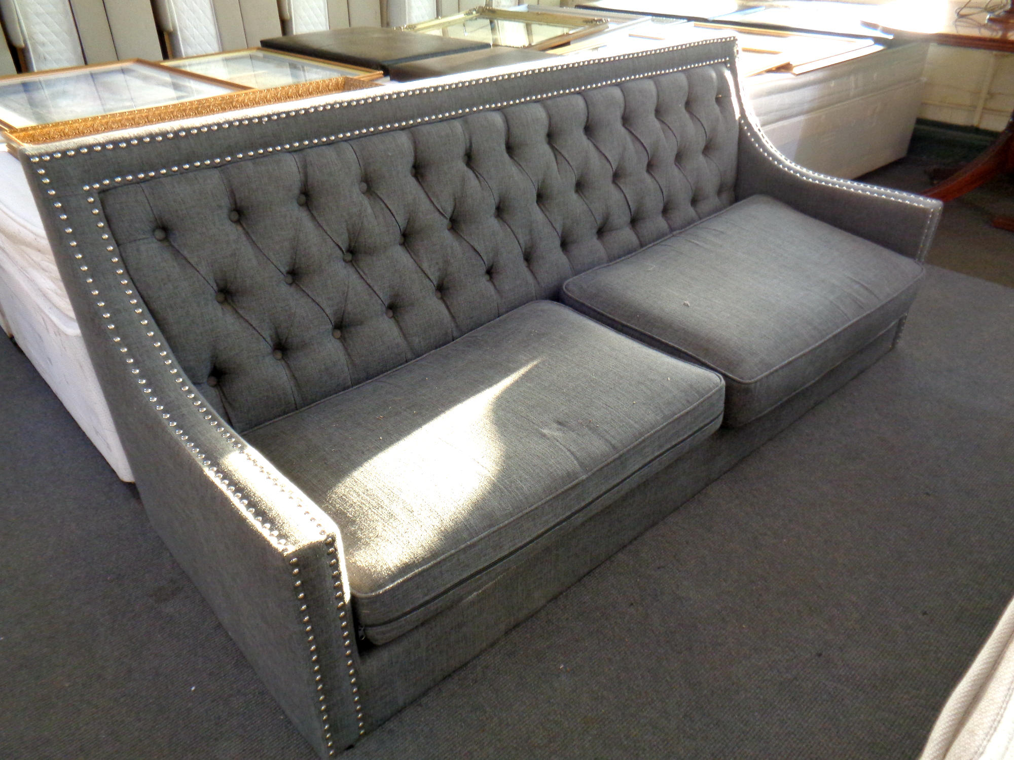 A contemporary button back settee in grey fabric