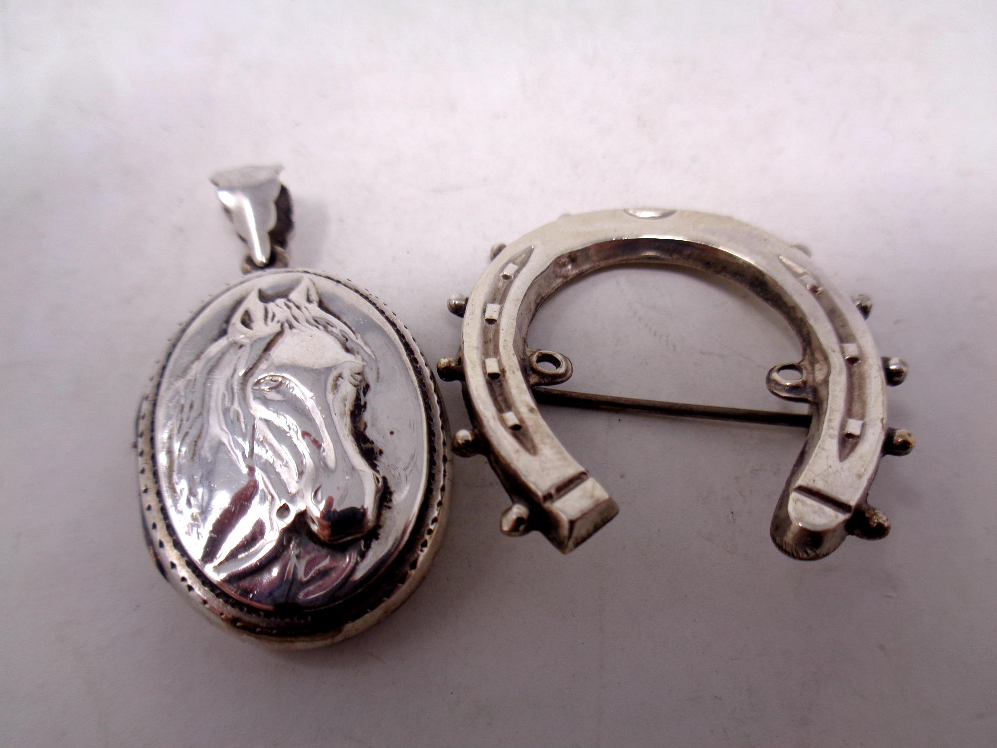 A silver horse locket and horseshoe brooch