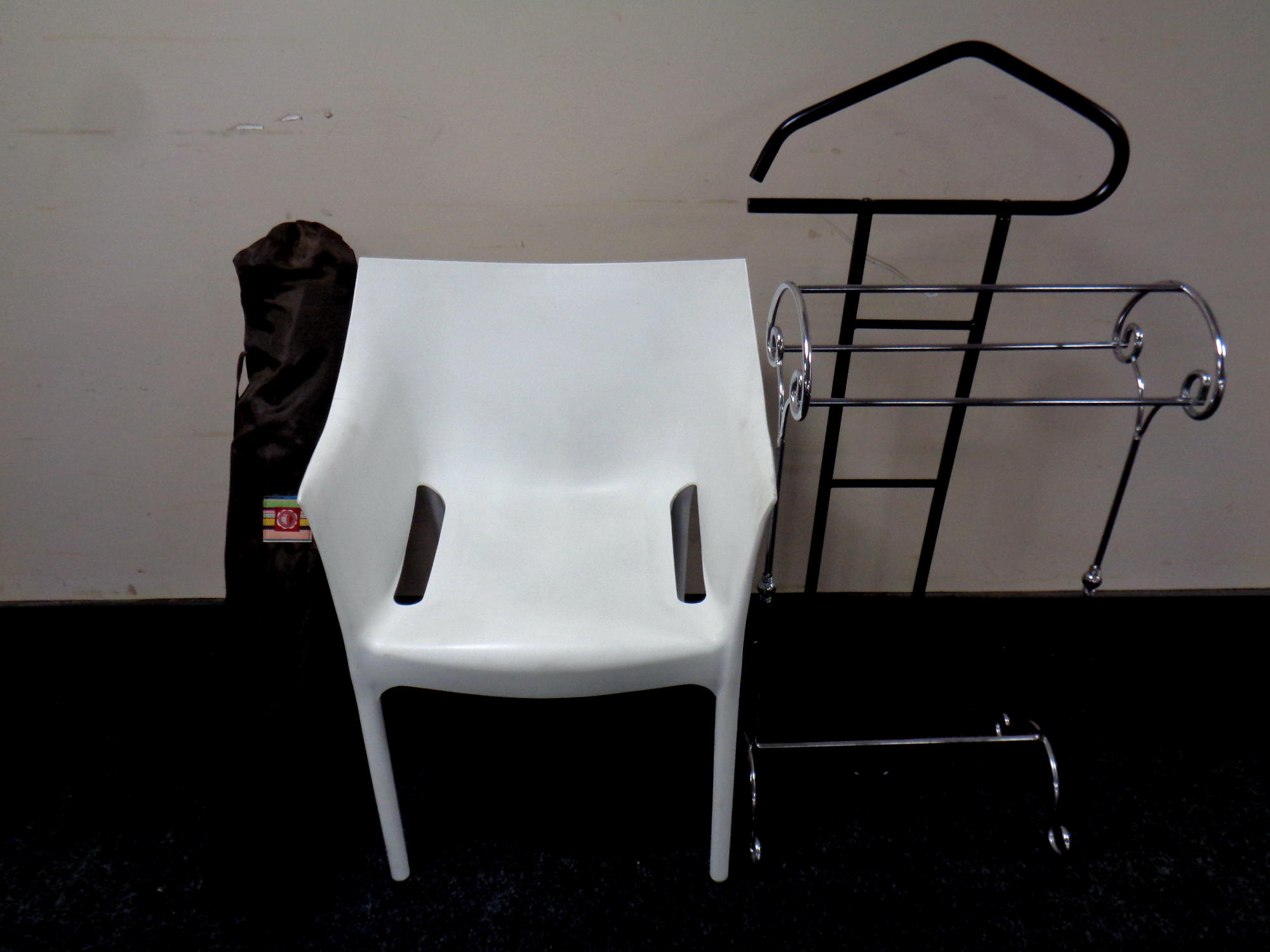 A contemporary white moulded plastic armchair together with a folding chair in carry bag,
