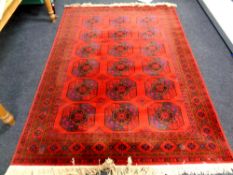 A machine made fringed rug of Bokhara design on red ground,