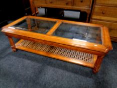 A colonial style coffee table with two glass inset panels and bergere shelf beneath,