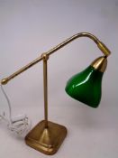 A retro style metal desk lamp with green glass shade on weighted base