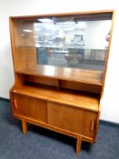 A mid 20th century teak sliding glass door display cabinet fitted cupboards beneath on raised legs,