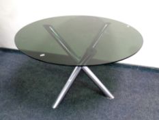 A contemporary circular smoked glass topped dining table on a metal tripod base,