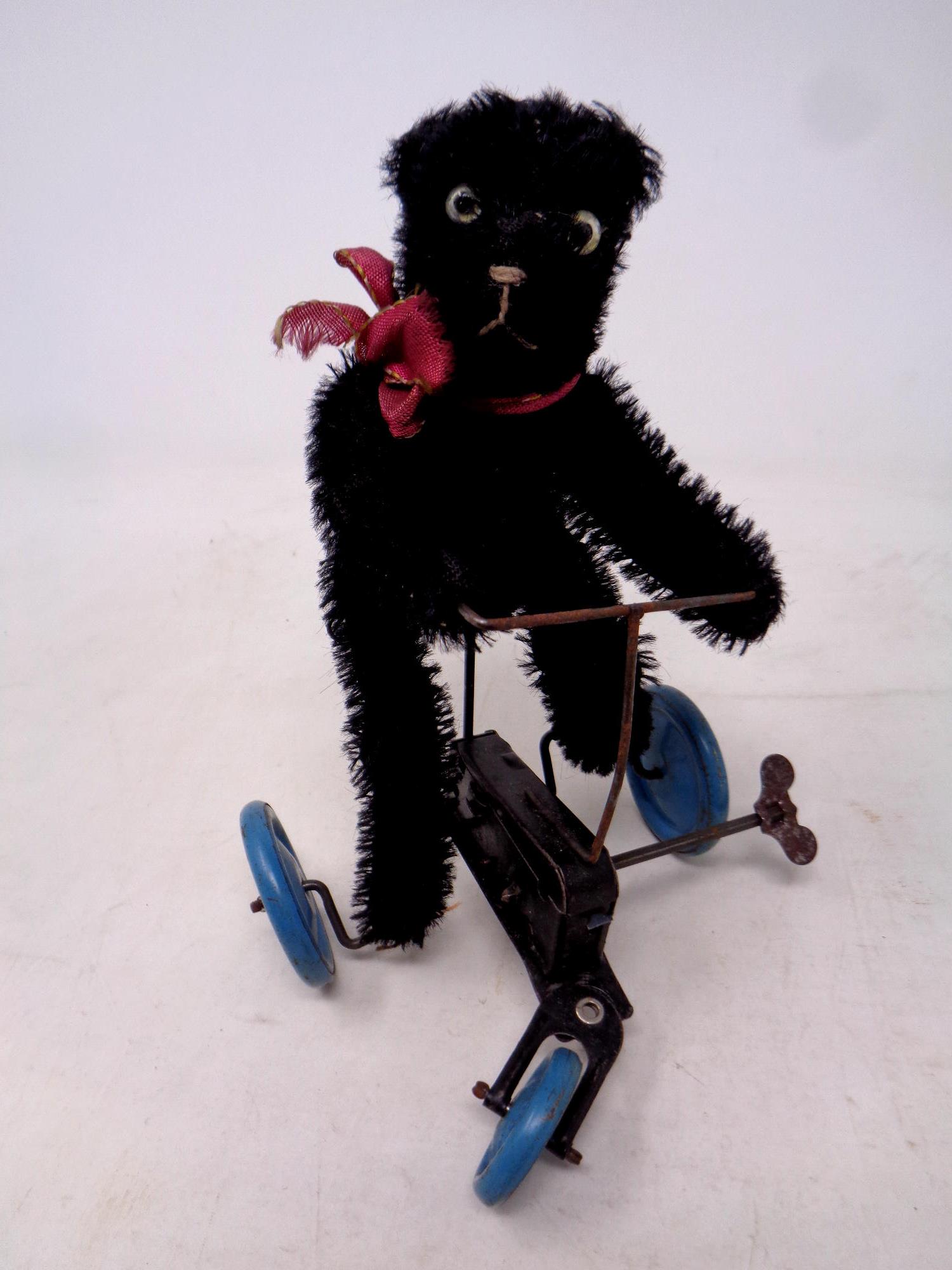 A mid 20th century mechanical wind up bear on tricycle