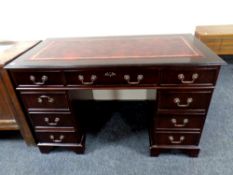 A reproduction mahogany pedestal desk with burgundy leather inset top,