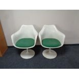 A pair of 1970s white plastic chairs on swivel metal bases