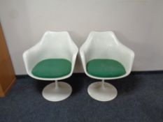 A pair of 1970s white plastic chairs on swivel metal bases