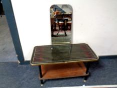A mid century two tier table together with a rectangular frameless mirror