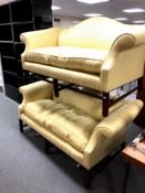 A pair of antique style two seater salon settees upholstered in golden striped fabric,