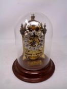 A contemporary brass skeleton clock under glass dome