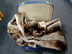 A mid century luggage case containing a faux fur coat