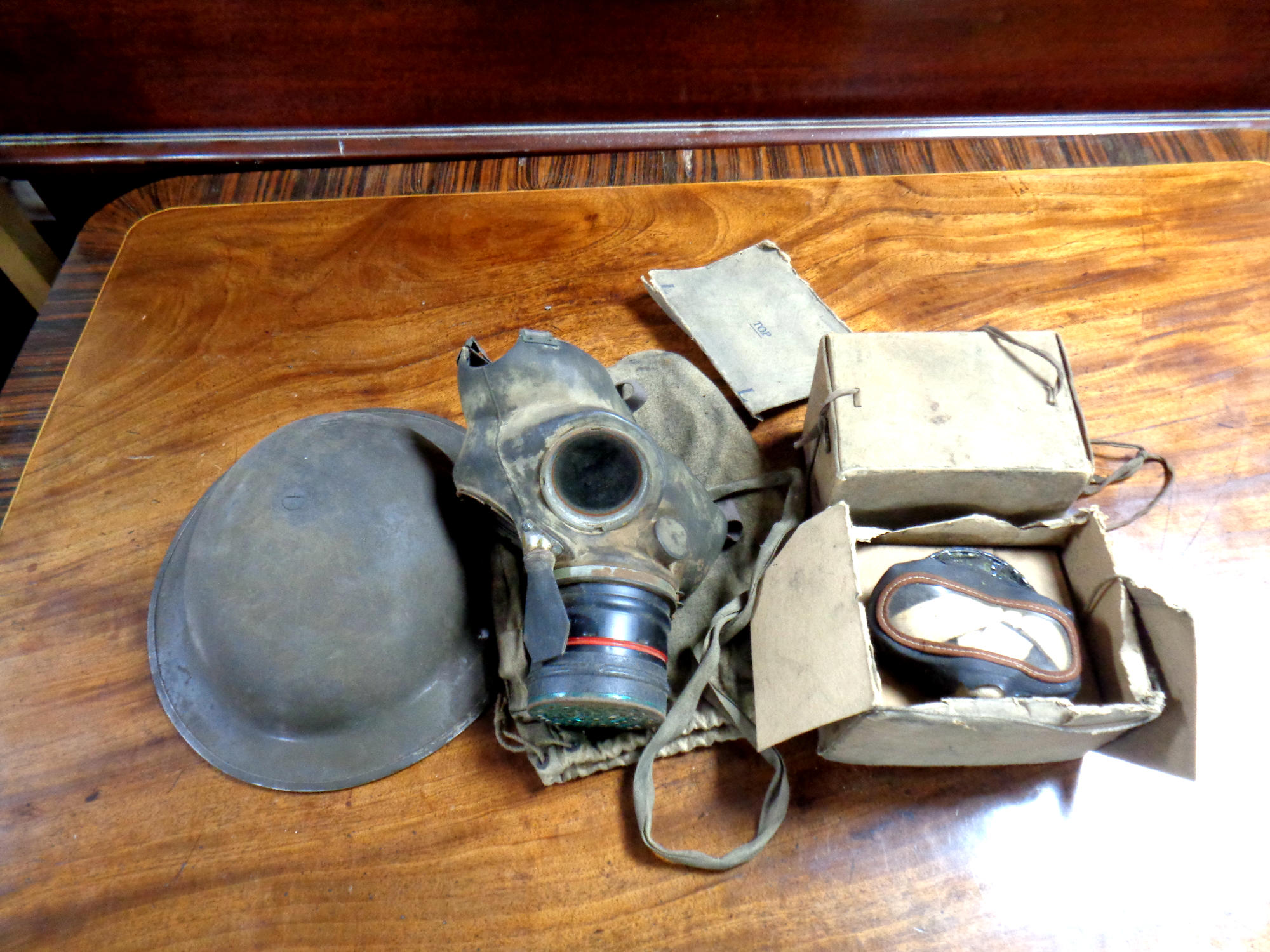 A Second World War tin helmet together with a quantity of gas masks
