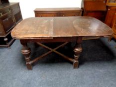 An Edwardian oak pull out dining table on bulbous legs together with a set of four oak dining