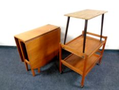 A teak drop leaf table together with an occasional table and a teak trolley