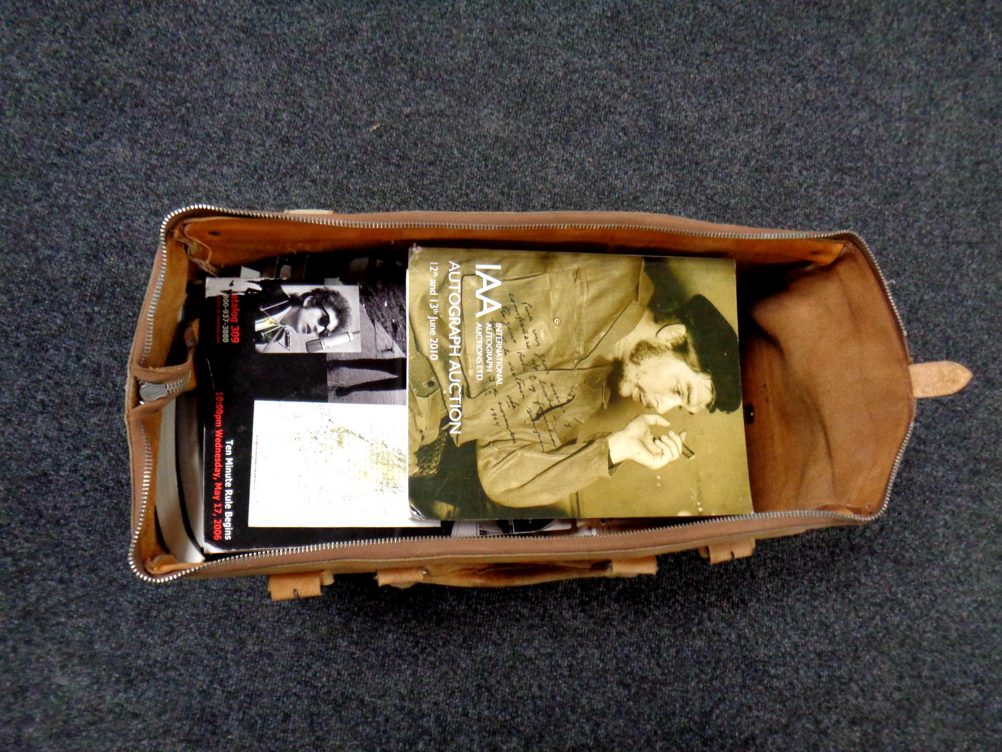 A brown leather holdall containing a large quantity of autograph auction's catalogues