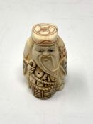 A Japanese carved bone netsuke - Village elder with a basket at his feet.