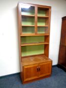 A mid century teak bookcase with glazed cabinet above,