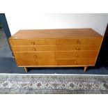 A mid century oak effect eight drawer low chest, width 131 cm, height 66.