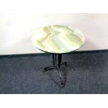 A circular onyx topped table on cast iron base,