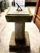 A metal sundial on concrete plinth