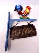 A cast iron cockerel wall bracket with welcome sign