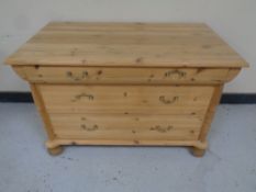 An antique pine three drawer chest on bun feet