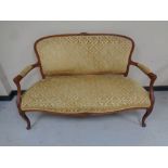 A carved beech framed French salon settee upholstered in a gold brocade fabric