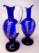 A pair of 19th century blue glass jugs with hand painted decoration,