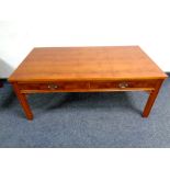 A yew wood coffee table on raised legs fitted with two drawers,